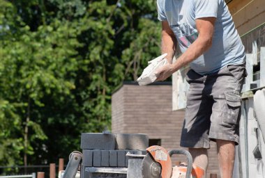 the bricklayer makes the facade of the house from gray bricks with cement and plaster at the construction site. High quality photo