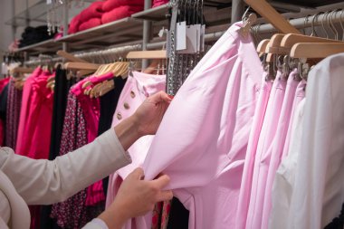 Mağazadaki kız askılık pembe pantolon seçiyor. Bin yıllık güzel kıyafetler, yüksek kaliteli fotoğraf.