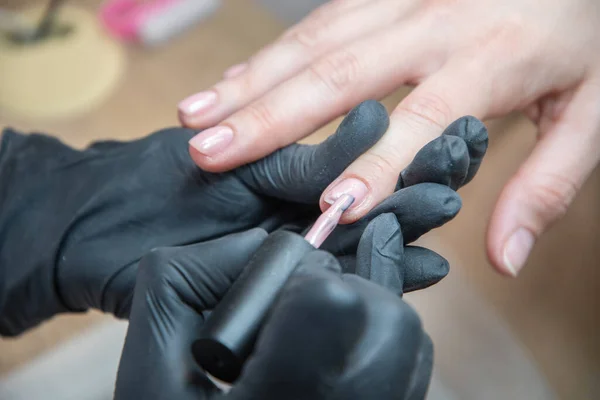 Stock image a master does a manicure to a client in a beauty salon and covers her nails with pink varnish. High quality photo