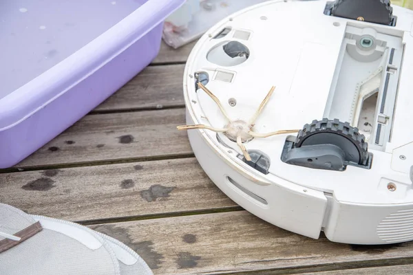 woman washing a trash can in a robot vacuum cleaner,planned maintenance of equipment for long-term use, High quality photo