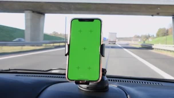 車のインテリア 道路ナビゲーションやマップのフロントガラスホルダーで緑の画面を持つスマートフォン 高品質4K映像 — ストック動画