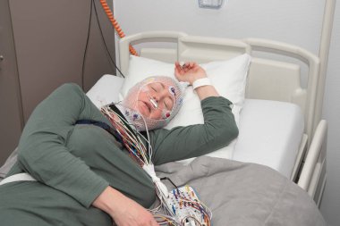 Middle aged woman measuring brain waves, examining polysomnography in sleep laboratory, High quality photo