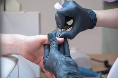 Siyah eldivenli manikürcü tırnak etlerini tırnak uçlarıyla kesiyor. Yüksek kalite fotoğraf