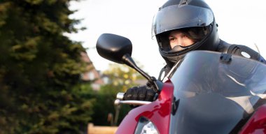 Kasklı genç bir motosikletli kız ve kırmızı motosiklet süren moto takım elbiseli, yüksek kaliteli bir fotoğraf.