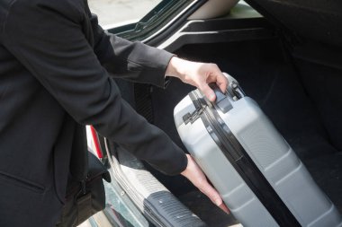 pretty young brunette putting suitcase in car trunk before going on vacation, High quality photo