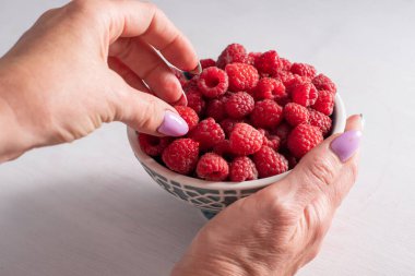 Kadın ellerinde bir kasede taze ahududu, yaz hasadı meyveleri ve taze meyveler, vitaminler, vejetaryen konsepti, yüksek kaliteli fotoğraf