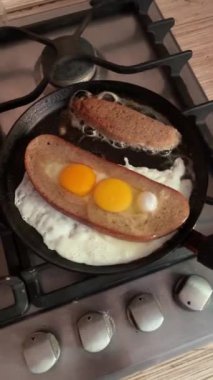 Ortada yumurta bulunan kızarmış ekmek, gaz sobasında kızartma tavasında kızartılır. Lezzetli besleyici kahvaltı, dikey 4k kalite görüntüler.