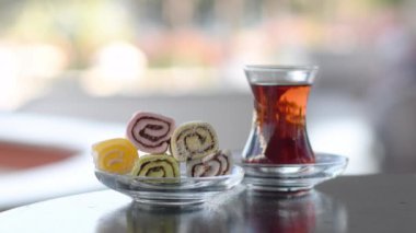 Geleneksel oryantal tatlılar Türk tatlısı, bir sokak kafesinde bir Türk çay bardağı cephaneliğinde, çok renkli salyangozlarla dolu, arka planda tanınmayan insanlar yürüyor.