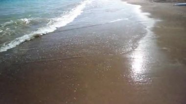 Gün batımında deniz kıyısında küçük köpüklü dalgalar gelir ve gider. Yaz tatilinde hoş bir tatil, dinlenme, dalgaların sesine doğru bir yürüyüş.