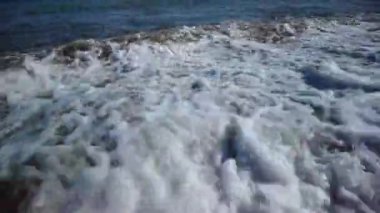 Gün batımında deniz kıyısında küçük köpüklü dalgalar gelir ve gider. Yaz tatilinde hoş bir tatil, dinlenme, dalgaların sesine doğru bir yürüyüş.