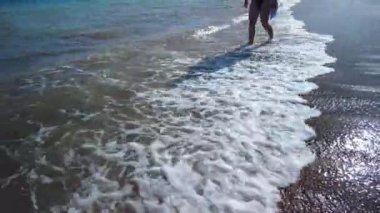 Genç kadın gün batımında kumlu sahilde yalınayak yürüyor. Gelen dalgaların köpüklü deniztaraklarını tekmeliyor. Yaz tatilinde keyifli bir tatil.