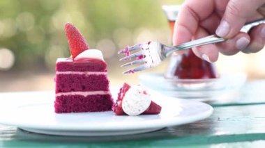 Çatal kullanan kadın, masada taze böğürtlenlerle süslenmiş kırmızı kadife pastayı, geleneksel Armudu bardağında bir fincan Türk çayını, yaz tatillerinde tatlı tatlı zamanı kırar.