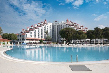Yeşil Max Oteli 'nin ana binası avludan, mavi su ve yeşil palmiye ağaçlarıyla çevrili, Belek, Türkiye, 29 Mayıs 2024.