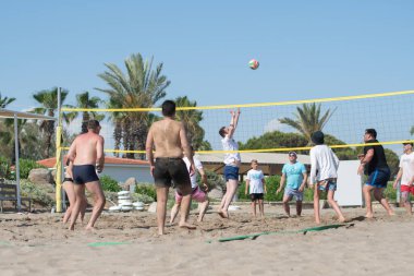 farklı etnik gruplardan turistler tatil sırasında deniz kenarında plaj voleybolu oynuyorlar, topu ağdan atıyorlar, Green Max Hotel, Belek, Türkiye, 29 Mayıs 2024