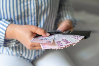 Cüzdanından 200 lira para çıkaran, çok parası olan ama Türkiye 'de enflasyonun çok az olduğu bir kadının elinde bulunan deri cüzdan.