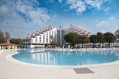 Yeşil Max Oteli 'nin ana binası avludan, mavi su ve yeşil palmiye ağaçlarıyla çevrili, Belek, Türkiye, 29 Mayıs 2024.