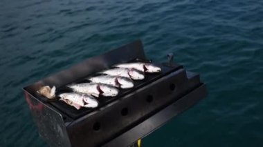 Teknede kızartılmış ızgara deniz balığı, Türkiye 'de tatil yapan turistler için en iyi akşam yemeğini hazırlayan denizciler, yüksek turizm hizmetleri, dalgalarda sallanan kayıklar,