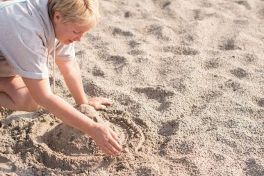 Kadın kumlu sahilde temiz havanın tadını çıkarıyor ve ıslak kumdan bir kale inşa ediyor. Tatilde denizde dinleniyor, yaz atmosferinde.