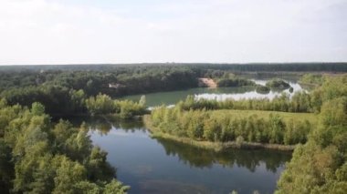 Belçika 'daki Lommel-Sahara Doğa Parkı' nda güzel bir gölü olan bir arazinin açık hava gözlem kulesinden görünen elektrik rüzgar türbinleri ufukta görünüyor..