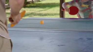 Sekiz yaşındaki sarışın çocuk babasıyla özel bir masa tenisi kortunda pinpon oynuyor çocuklar için eğlenceli yaz sporları, Türkiye 'deki tüm aileyle unutulmaz yaz tatilleri.