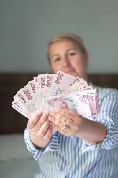 stock image woman holds large stack of 200 Turkish lira bills in front of her, spreads it with a fan and shows it to the camera, a lot of money, but little value, high inflation in Turkey