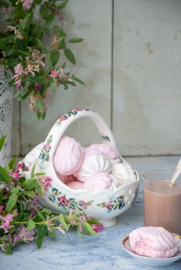 Bir vazo dolusu vanilyalı şekerlemeyle, bir bardak sütlü kahveyle, ahşap masa üzerinde pembe çiçek dallarıyla dolu vazonun yanında, konsept köy yaşam tarzıyla...,