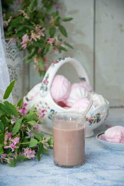 Bir vazo dolusu vanilyalı şekerlemeyle, bir bardak sütlü kahveyle, ahşap masa üzerinde pembe çiçek dallarıyla dolu vazonun yanında, konsept köy yaşam tarzıyla...,