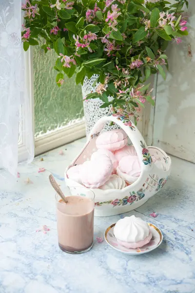 Bir vazo dolusu vanilyalı şekerlemeyle, bir bardak sütlü kahveyle, ahşap masa üzerinde pembe çiçek dallarıyla dolu vazonun yanında, konsept köy yaşam tarzıyla...,