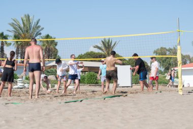 farklı etnik gruplardan turistler tatil sırasında deniz kenarında plaj voleybolu oynuyorlar, topu ağdan atıyorlar, Green Max Hotel, Belek, Türkiye, 29 Mayıs 2024