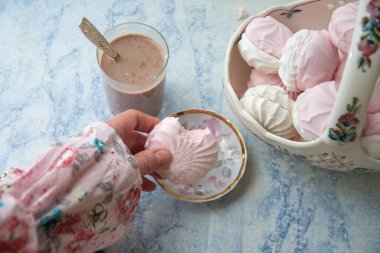 Kadın eli ısırılmış vanilya şekeri, narin hayat dolu vazo dolusu vanilyalı marşmelov ve sütlü bir bardak kahve,