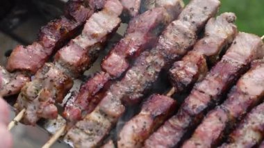 Kömürde et kebabı yapan genç bir adam, ARROSTICINI - tipik güney İtalyan mutfağı, yazın evin yakınındaki terasta lüks bir piknik, barbeküden aromatik dumanlar yükseliyor.,