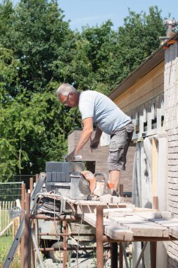the bricklayer makes the facade of the house from gray bricks with cement and plaster at the construction site. High quality photo