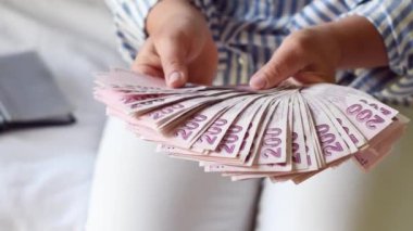 Kadın, önünde 200 lira banknot yığını tutuyor, bir vantilatörle yayıyor ve kameraya gösteriyor ki Türkiye 'de çok para ama çok az değer, çok az enflasyon var.