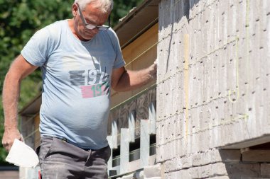 the bricklayer makes the facade of the house from gray bricks with cement and plaster at the construction site. High quality photo