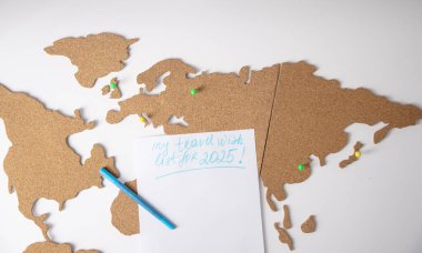 2025 seyahat dilek listesi mantar panoya yerleştirilmiş, renkli raptiyeli dünya haritası, beyaz arka plan, gelecek yolculuk planı,