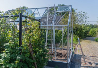 Bahçıvan bahçesindeki seranın çatısına cam döker, konsept yapar ve küçük bir bahçe arazisinde sebze yetiştirir.,