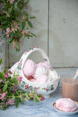 Bir vazo dolusu vanilyalı şekerlemeyle, bir bardak sütlü kahveyle, ahşap masa üzerinde pembe çiçek dallarıyla dolu vazonun yanında, konsept köy yaşam tarzıyla...,