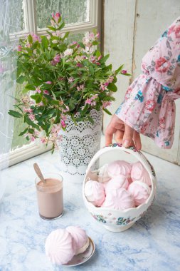 Kadın eli bir sepet dolusu vanilyalı şekerlemeyi pembe çiçekli vazonun yanında, ev yemeği ve köy hayatı kavramının yanında tutuyor.,