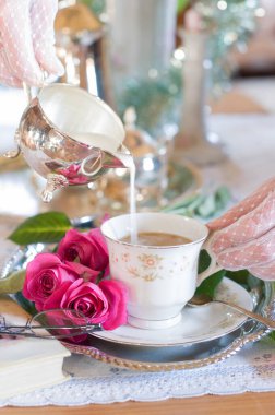 İngiliz usulü çay molası, beyaz dantel eldivenli kadın elleri porselen bardağa krema döküyor, antika natürmort hayat, kahve servisi, sığ alan derinliği, aydınlık ve hava, Noel havası.,