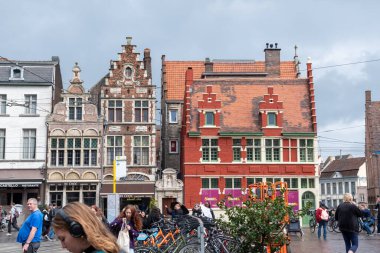 Geleneksel mimarisi olan güzel tarihi tuğla binanın manzarası, 24 Eylül 2024 'te yağmur, Gent, Belçika' dan sonra yayalar ve arabalar arasında sokakta bisiklet süren bir bisikletçi.,