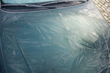 Drawings of nature frost patterns on the hood of a car at temperatures below zero, outside the car on an abstract winter pattern, clipart