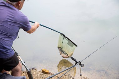 Havuzda başarılı bir balık avı, elinde kupa olan mutlu bir balıkçı, balık tutmakla meşgul, balık tuttuktan sonra balık ağla avlanıyor.,