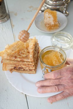 A man pours honey on pancakes and drinks tea from a samovar, Russian tradition of celebrating Maslenitsa. High quality photo clipart