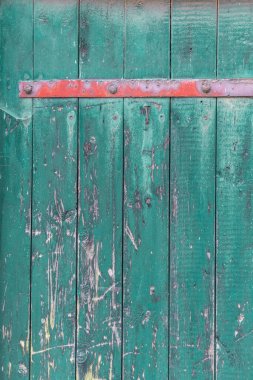 Wooden door made of old wooden planks in turquoise color with a red metal strip on top, the textured surface emphasizes the vintage charm and character. clipart