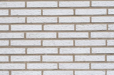 Dar beyaz seramik tuğlalardan yapılmış duvar, desenli ve tekdüze yüzey, çeşitli tasarım ve mimari projeler için ideal.,