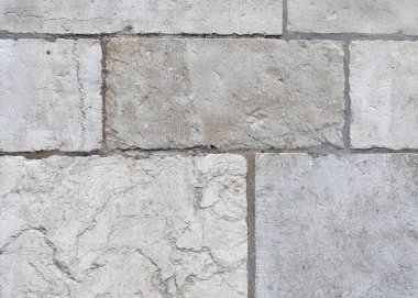 Eski, yıpranmış duvar çeşitli şekillerde, karmaşık dokuları olan büyük doğal gri taşlarla kaplı taşlar havan topuyla doldurulmuş görünür dikişlerle döşenmiş.,