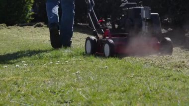 Bahçıvan çimenlikteki yosunları çıkarmak için korkutucu şeyler kullanır. Arkasından çekme makinesi, bahçenin durumunu ve görünümünü iyileştirme, güneşli bahar günlerinde mevsimlik bahçe işleri.,
