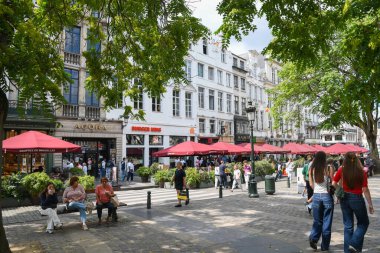 Belçika 'nın tarihi Grand Place' inde gezen turistler, Belçika 'nın güneşli bir yaz günü Belçika' nın başkenti Brüksel 'de yemek ve alışveriş yaparken Belçika atmosferinin tadını çıkarıyorlar.