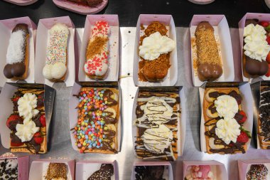 Krem şantili sıra sıra ve normal waffle 'lar, çikolatalı çeşitli soslar, renkli süsler, taze çilekler veya muz, Brüksel, Belçika, 5 Ağustos 2025,