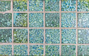 Kare harçlı parlak yeşil ve mavi cam mozaik fayanslar desenli bir yüzey yaratarak tasarıma dekorasyon için mükemmel bir sanatsal görünüm kazandırıyor.,